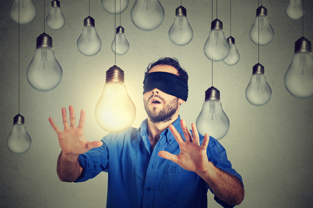 blindfolded man walking through light bulbs