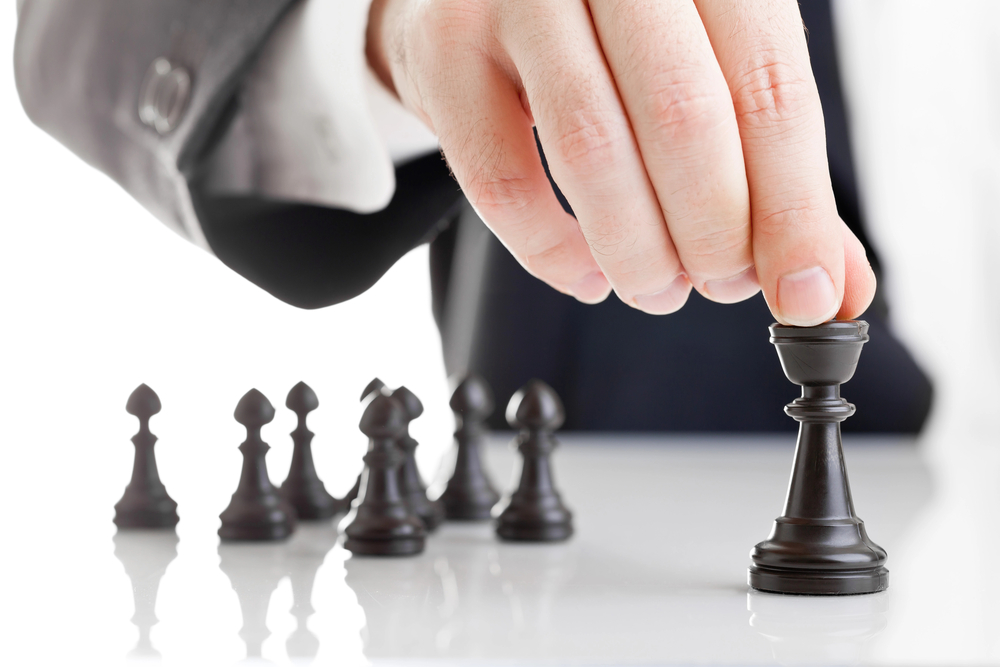 Image of businessman's hand moving a chess piece symbolising strategic dental practice growth 