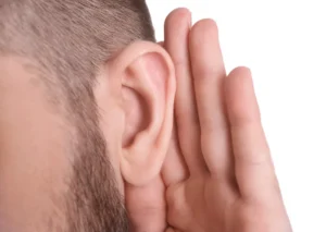 A man with his hand cupped to his ear, symbolising listening, attention, and openness to hearing others.